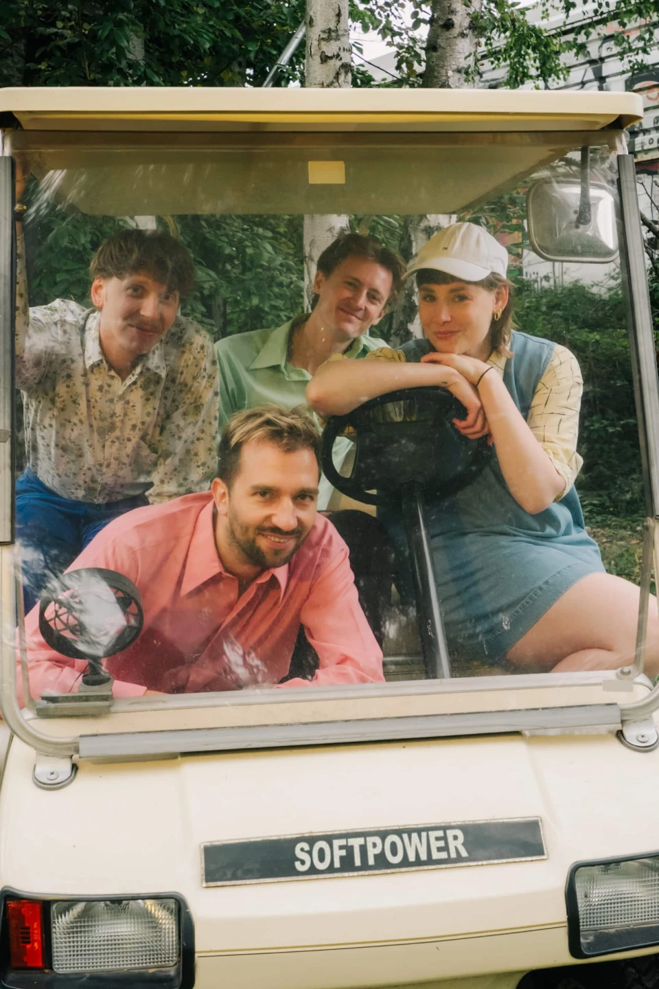 Four people smiling inside a white golf cart labeled 